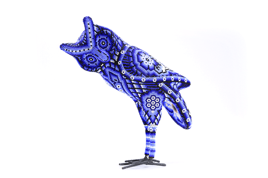 Obra de arte huichol de un búho en perfil, trabajado con chaquiras en variaciones de azul, creando un efecto vibrante y detallado que capta la esencia espiritual del búho en la cultura wixárika, simbolizando misterio y conocimiento ancestral