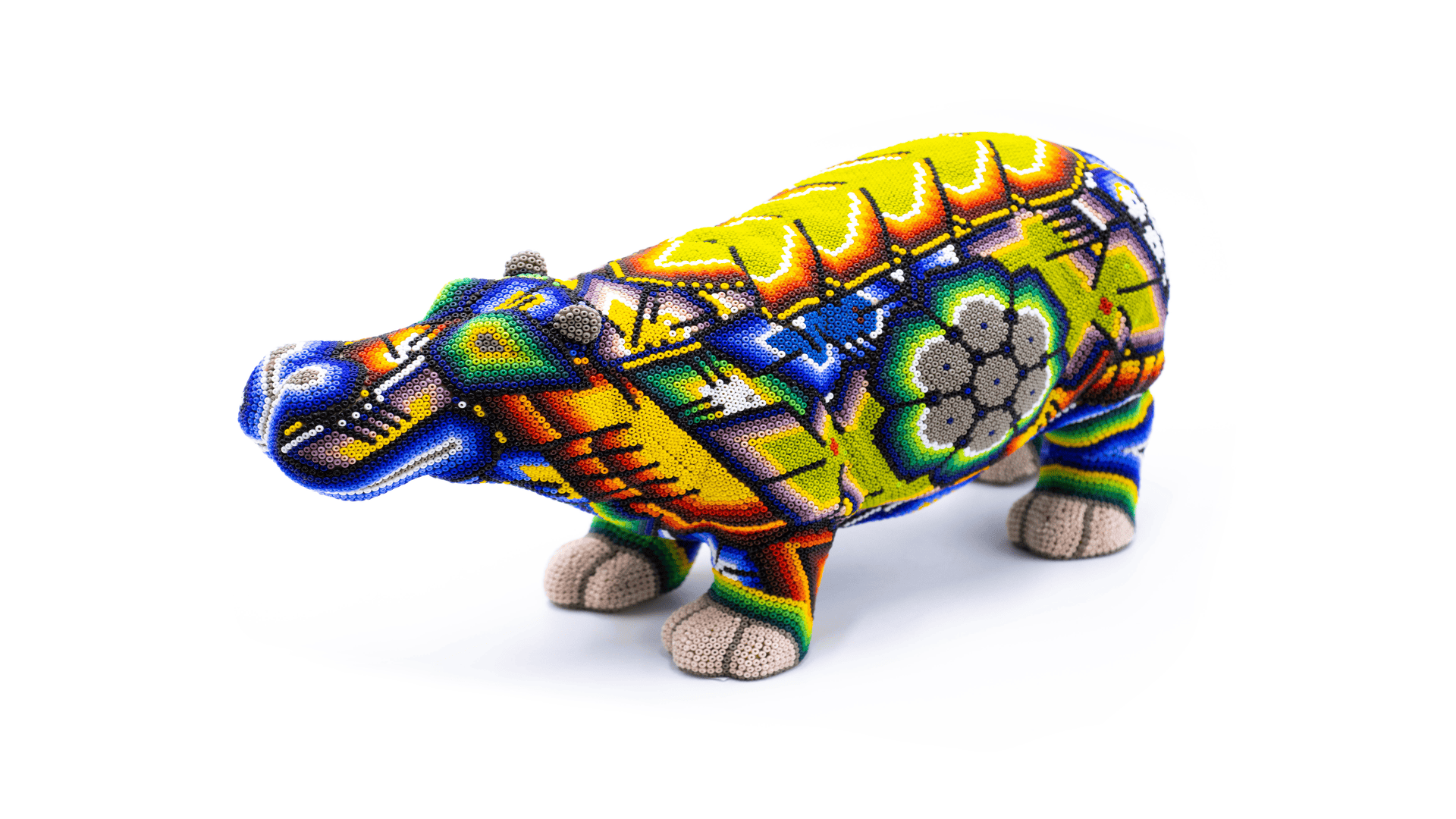 Vibrant hand-beaded hippopotamus figurine in a dynamic stance, featuring a bright yellow and blue color scheme with traditional Huichol-style patterns and floral motifs, expertly crafted and isolated on a white background.