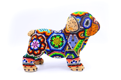 Figura artesanal de un bulldog bebé huichol, con un detallado trabajo de chaquiras en un arcoíris de colores, incluyendo diseños florales y estrellas, reflejando la riqueza cultural de la artesanía wixárika