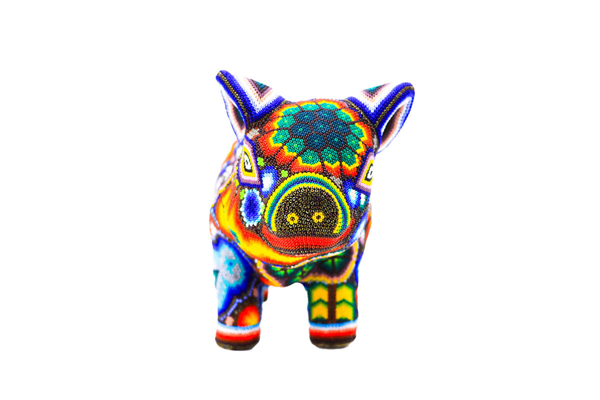 Artesanía huichol de un cerdo, vibrante y colorida, meticulosamente decorada con patrones de chaquiras que forman diseños tradicionales wixárikas, incluyendo estrellas y flores en una amplia gama de colores brillantes