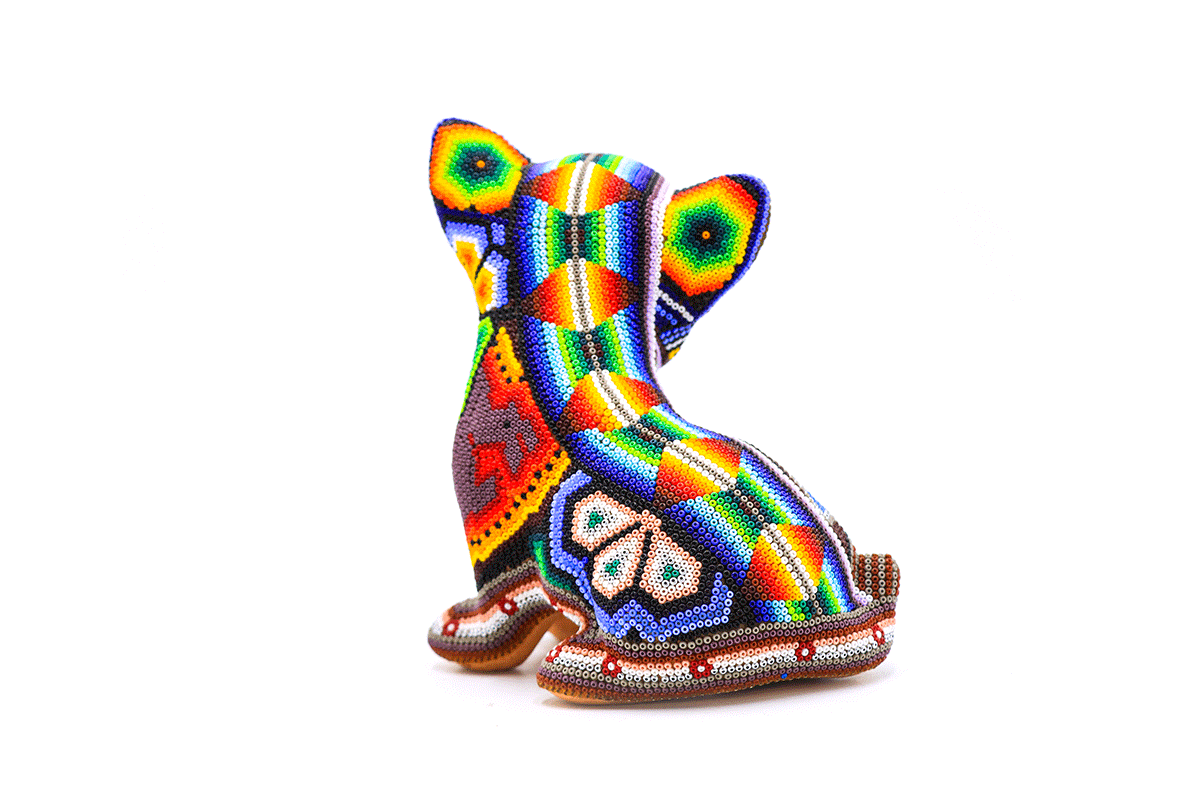 Artesanía Huichol de espalda detallada de un perro chihuahua mini, con cuentas multicolores formando patrones Wixárika en un fondo neutro