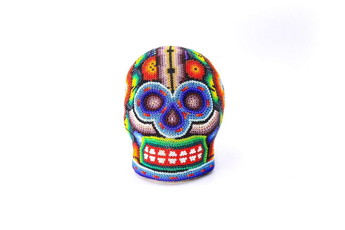 Cráneo huichol artesanal, intrincadamente cubierto con un patrón de chaquira que representa la iconografía wixárika, destacando un par de ojos y una nariz en un rostro estilizado sobre un fondo multicolor