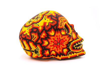 Cráneo grande huichol visto de lado, decorado con un vibrante diseño de chaquira que destaca una flor central en rojo y naranja, rodeada de patrones tradicionales wixárika que simbolizan el ciclo de la vida y la muerte