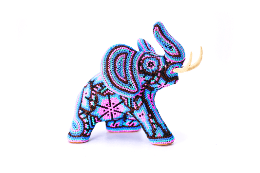 Escultura de elefante Huichol perfil derecho adornada meticulosamente con cuentas de colores vibrantes formando patrones Wixárika tradicionales, con colmillos prominentes en contraste