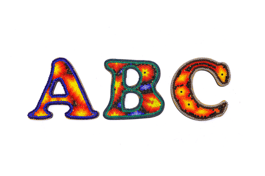 Letras del alfabeto 'A', 'B', 'C' decoradas con técnica de arte huichol, cada una presentando un mosaico de cuentas con patrones vibrantes y colores brillantes que resaltan sobre un fondo blanco