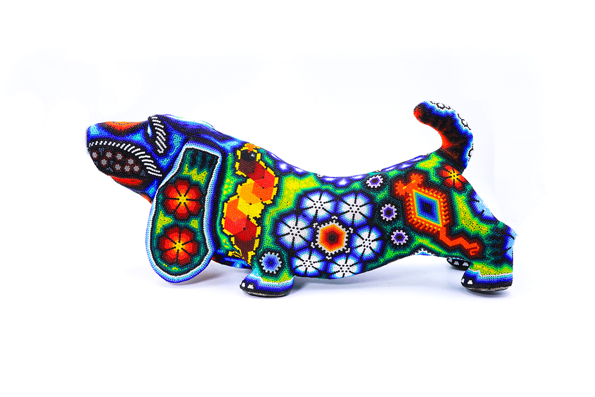 Figura artesanal de perro salchicha con diseño Huichol, mostrando una paleta de colores intensos y motivos tradicionales Wixaritari