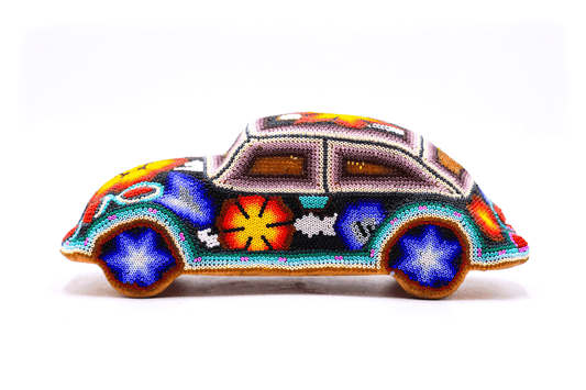 Lateral de un vehículo wixárika colorido, cubierto por un trabajo detallado de cuentas en un arreglo de diseños tribales, flores y patrones abstractos en una gama de colores cálidos y fríos que resaltan la artesanía huichol
