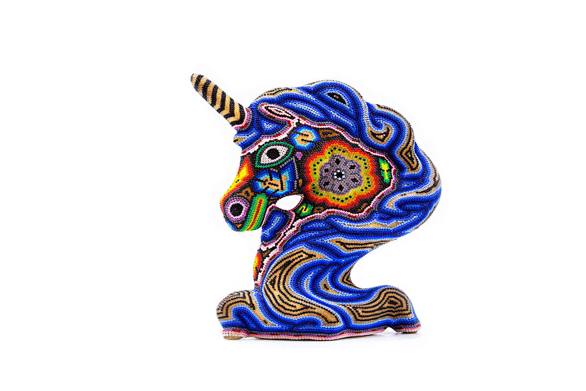Figura de una cabeza de unicornio con cuerno y orejas en alto, adornada con chaquiras que forman diseños vibrantes y espirales, en una gama de colores que incluye azul, naranja y verde, contra un fondo blanco