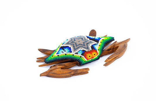 Artesanía de cangrejo con patas y pinzas adornadas con un trabajo detallado de cuentas al estilo Huichol, con colores vivos sobre un fondo blanco neutro