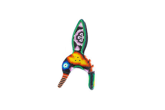 Figura artesanal de colibrí decorado con chaquira en técnica de arte Huichol sobre fondo blanco, mostrando un patrón de colores vivos que incluye naranja, verde y puntos de luz en azul y blanco
