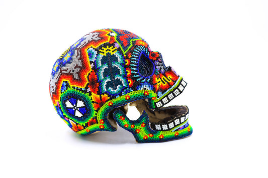 Cráneo artesanal Huichol decorado con patrones de chaquiras coloridas, destacando el arte milenario Wixárika en una representación moderna y estética
