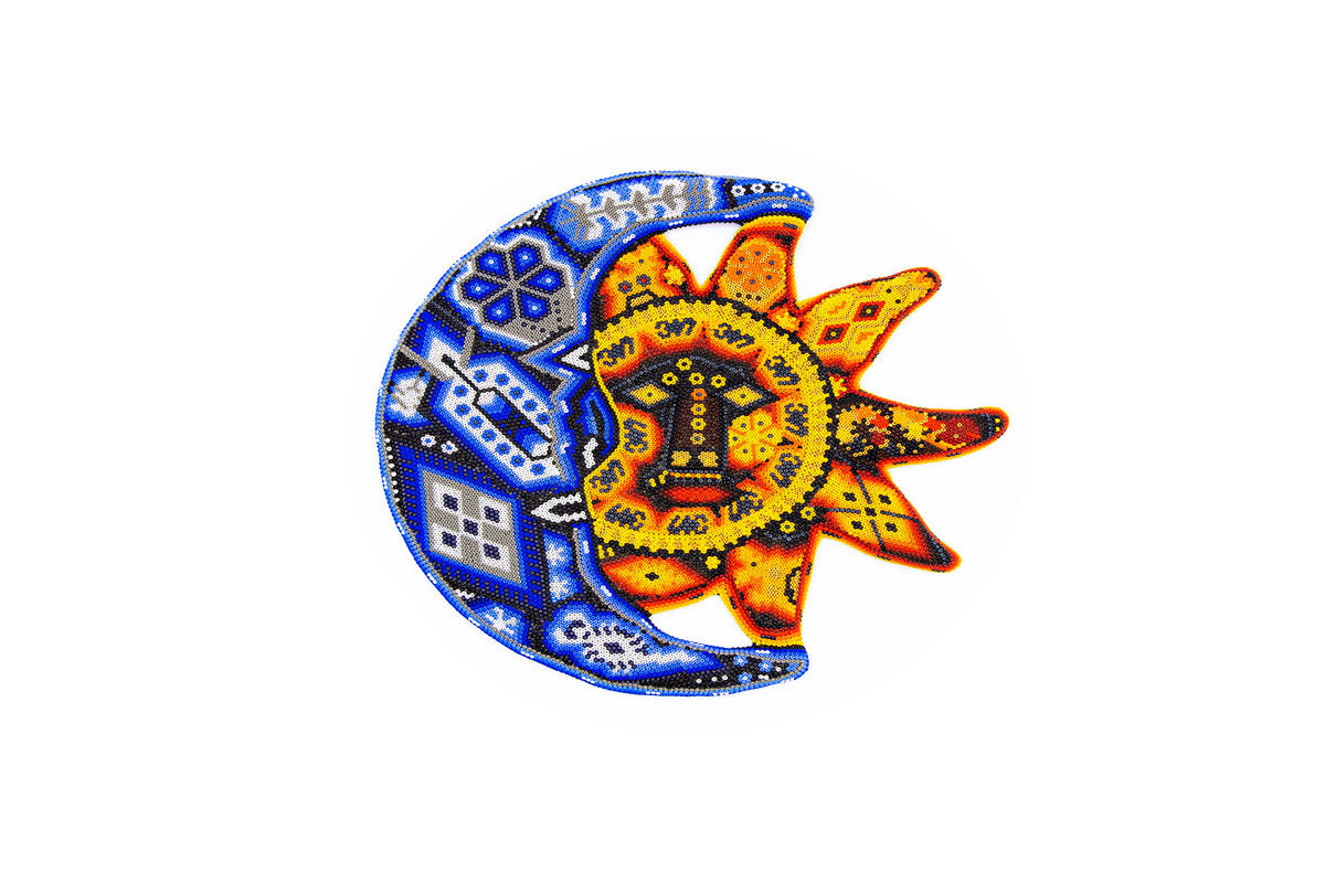 Artesanía huichol representando un eclipse, con la luna en chaquiras azules y el sol en amarillo y naranja, ambos con diseños tradicionales geométricos y puntos en contraste, sobre un fondo blanco