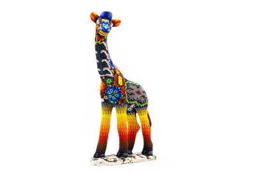Detalle lateral de una figura de jirafa decorativa, con intrincados patrones de cuentas en colores vibrantes. El trabajo artesanal muestra formas geométricas y florales que resaltan sobre un fondo multicolor, con un diseño que fluye a lo largo de todo el cuerpo de la figura