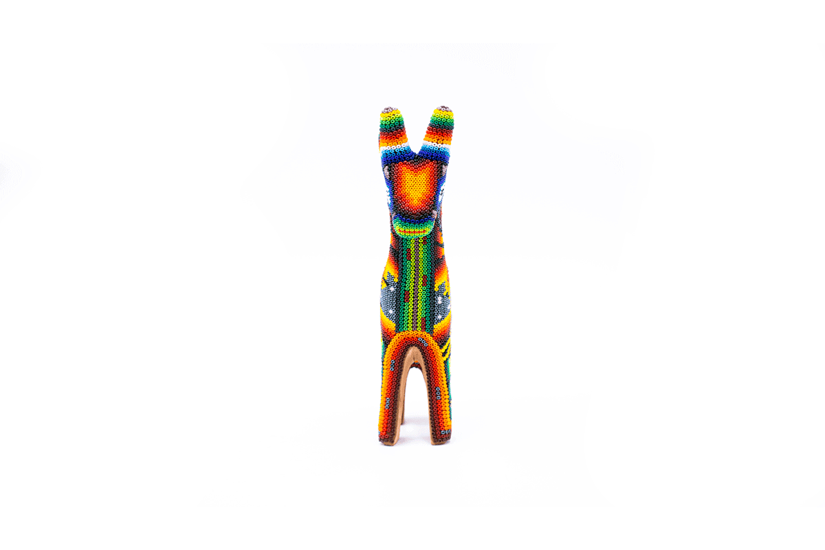 Escultura detallada de una jirafa en miniatura en estilo huichol, con intrincados patrones de cuentas que destacan en tonalidades de azul, naranja y verde, con fondo blanco puro