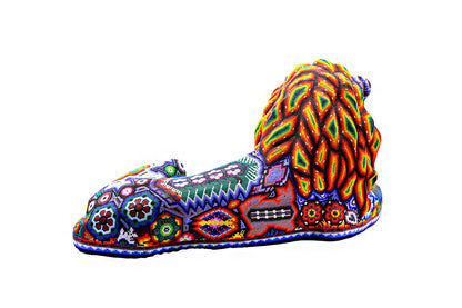 León artesanal Huichol único, acostado y decorado con miles de cuentas de colores formando patrones simbólicos y espirituales, representando la fauna y el arte Wixárika