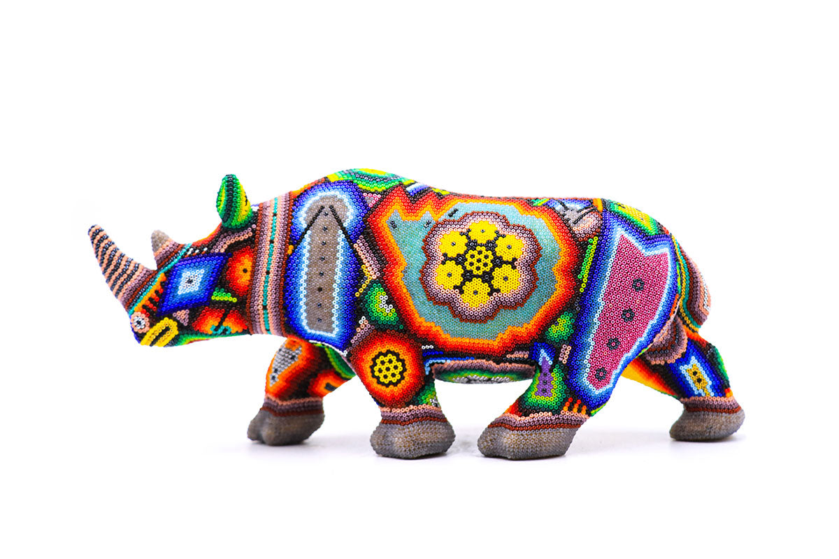 Arte Huichol en forma de rinoceronte, cuidadosamente adornado con cuentas de colores formando diseños geométricos, una pieza única de artesanía Wixarika