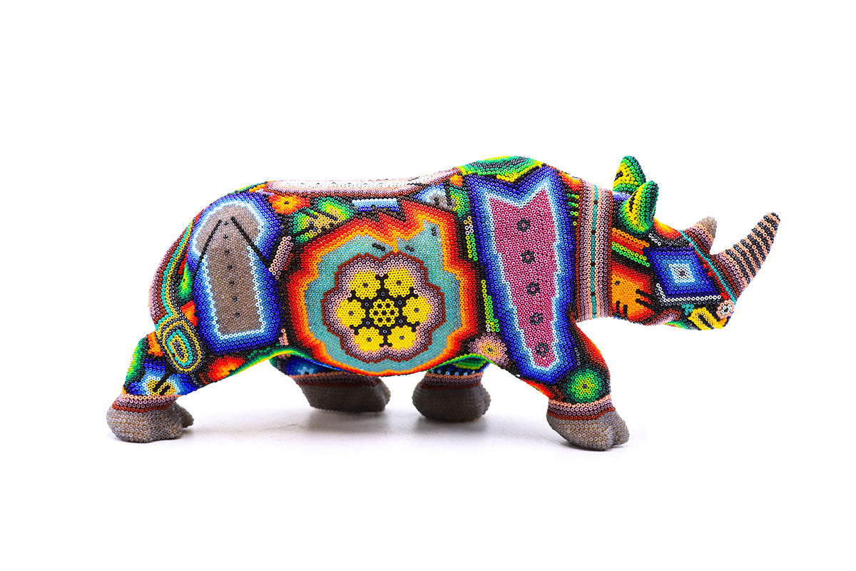 Figura artesanal Wixarika de un rinoceronte, cubierta con un intrincado patrón de cuentas que refleja la cultura y el arte indígena Huichol, ideal para decoración de interiores