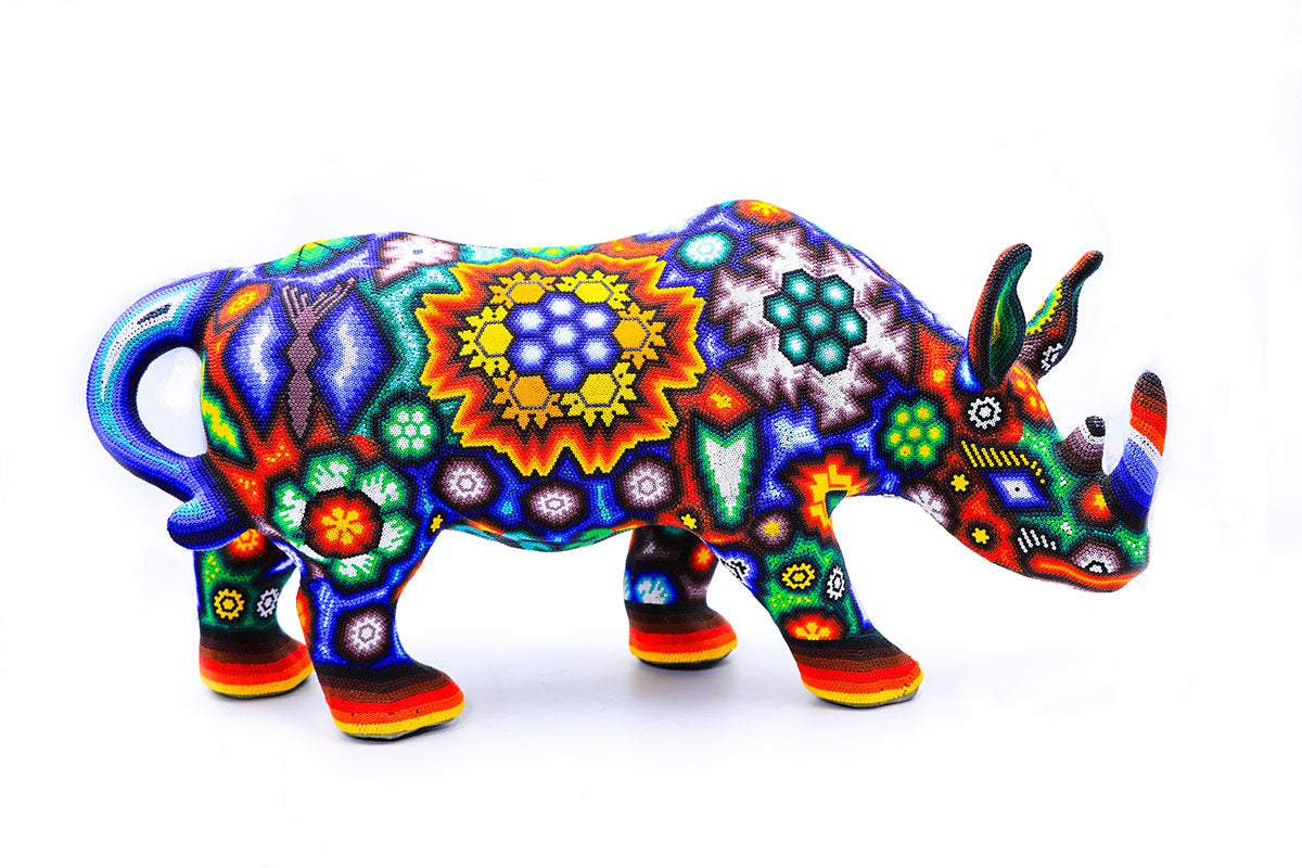Escultura artesanal Huichol en forma de rinoceronte, decorada con un mosaico de cuentas multicolores y patrones simétricos, representativos de la cosmogonía Wixárika