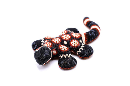 Escultura de salamandra Huichol hecha a mano, con un diseño detallado de cuentas en patrones tradicionales Wixarika, en tonos rojos y negros, perfecta para decoración artística y coleccionistas de arte indígena