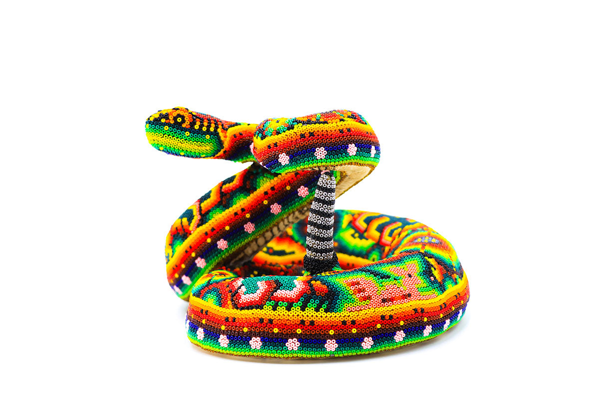 Intrincada escultura Huichol en forma de serpiente de cascabel, adornada con un diseño colorido de cuentas que representan la mitología y el arte Wixárika