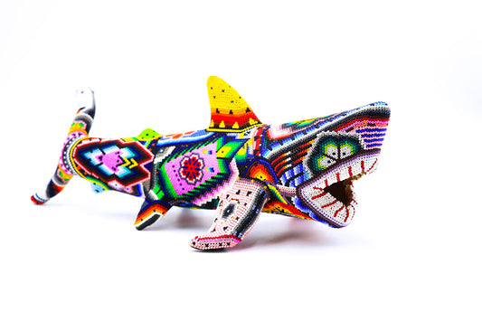 Obra de arte Huichol detallada con diseño de tiburón, mostrando un mosaico de colores y formas tradicionales Wixárika, resaltando el arte y la artesanía indígena mexicana