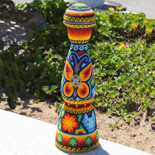 Botella de tquila azul con arte huichol enchaquirado